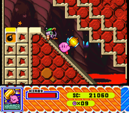A imagem mostra uma cena de jogo do Kirby Super Star para Super Nintendo. Kirby, o personagem rosa, está usando um martelo e subindo uma rampa inclinada feita de blocos hexagonais vermelhos. No topo da rampa, há mais blocos e uma área escura que parece ser uma caverna ou passagem. Ao lado de Kirby, está o Gim, um personagem menor com um boné verde. Na parte inferior da tela, há uma interface do jogo mostrando a barra de energia de Kirby, a pontuação (21060), o número de vidas (x09) e um ícone da habilidade, hammer. A paleta de cores é vibrante, com tons de vermelho, laranja e amarelo dominando a cena. O estilo gráfico é típico dos jogos de 16 bits, com pixels nítidos e um design colorido.