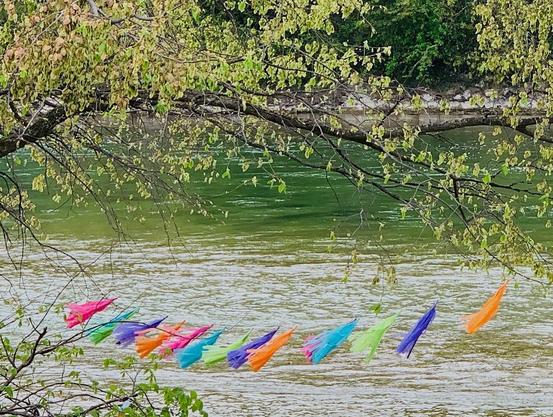 Bunte Fähnchen an Zweigen, dahinter der Fluss.
