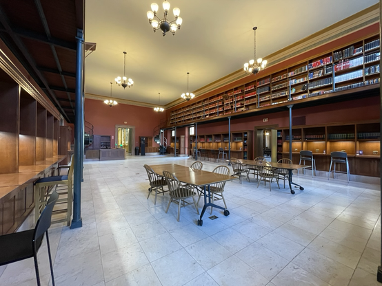 An empty study room in the Boston public library. There are tables, working nooks and a spiral staircase leading to book stacks