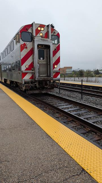 A double decker commuter train pulls into the station on a rainy day in Buffalo Grove, Illinois, USA