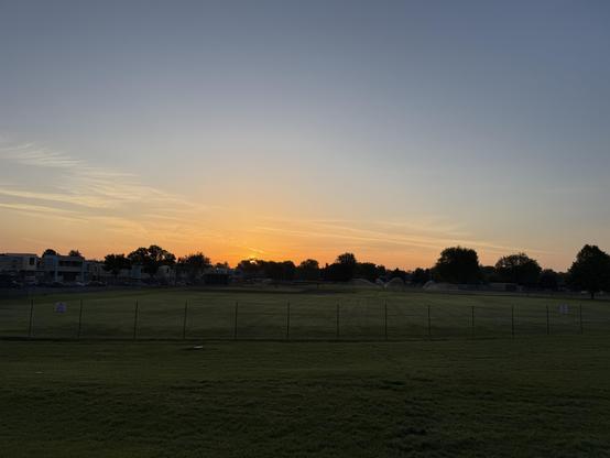 A sunrise lit sky over a school sports field