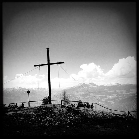 Una grande croce sulla cima del monte e le cime delle montagne in lontananza