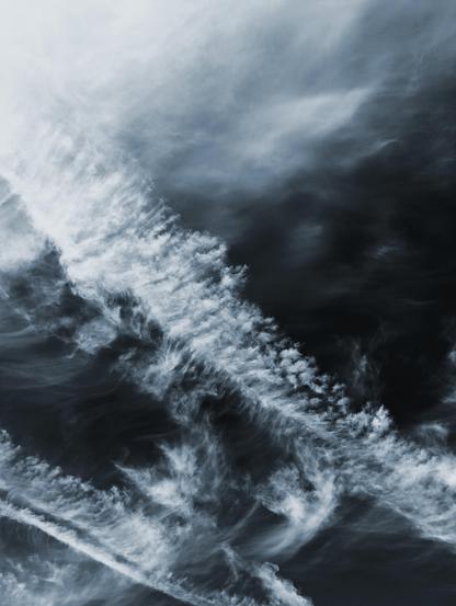 A photo of the sky in a monochrome, almost black and white style, but with a touch of blue. The clouds are wispy and extravagant.