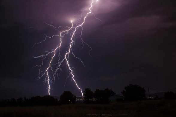 Twin lightning bolts split the night sky in parallel, striking the ground side by side during a thunderstorm over Spain.