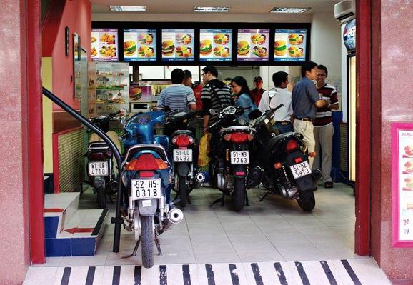 experts conference: photograph of a "drive-by" fast food restaurant with customers' motorbikes parked inside. Photo attribution: Flickr user jannem