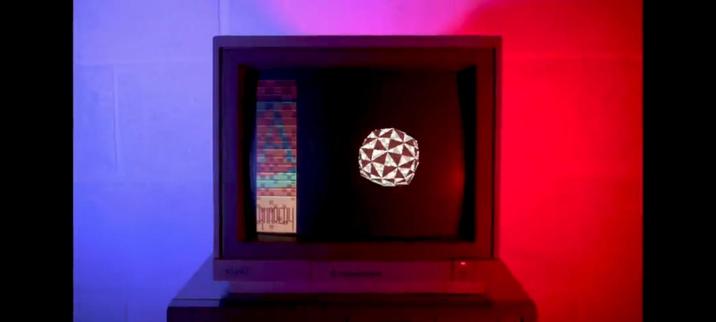 The screencap features an old-style CRT monitor placed on a stand, with a distinctive geometric pattern, displayed on its screen. The monitor is illuminated by a red light on the right and a blue light on the left, creating a striking contrast.

The screen shows a black background with a white, faceted spherical object in the center, resembling a dodecahedron. To the left of the sphere, there is a vertical bar composed of colorful, pixelated blocks, with a label at the bottom that reads "Mandelbrot." The monitor's brand is visible at the bottom, and the overall setting suggests a retro or artistic display.

 Ovis2-8B

🌱 Energy used: 0.157 Wh