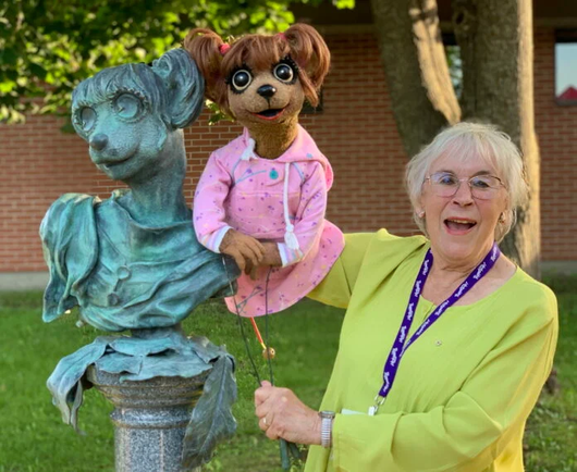Photo of Noreen Young with one of her mouse puppets, beside a statue of same.  (I recognize the mouse, but can't place it. It's not Muffy from Today's Special, but similar). 