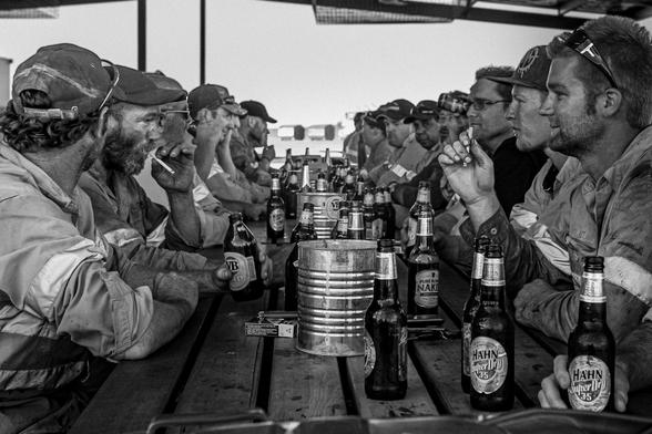 Australian mining workers at the wet mess, sitting around a table, chatting and drinking beers