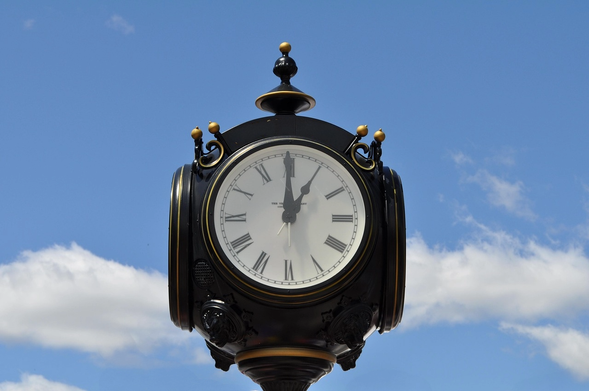 Townhall style clock shows 13:00 against a blue sky