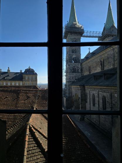 Das Bild zeigt eine Aussicht aus einem Fenster auf eine historische Stadtlandschaft. Im Vordergrund ist ein Fenster mit einem schwarzrahmten Fenster mit sechs Gittern zu sehen. Durch das Fenster ist ein Teil eines gotischen Kirchturms mit zwei spitzen Türmen zu erkennen, die mit Stahlrahmen für Renovierungsarbeiten umgeben sind. Der Turm hat eine steinerne Fassade mit architektonischen Details und einem Kreuz auf dem Dach. Neben dem Turm ist ein Teil eines Kirchengebäudes mit einer massiven Steinmauer und einem großen Tor zu sehen. Im Hintergrund ist ein Gebäude mit einem Dach aus roten Ziegeln und einer Fassade aus gelbem Stein zu sehen, das möglicherweise ein historisches Gebäude ist. Der Himmel ist klar und blau, was auf einen sonnigen Tag hinweist.

Bereitgestellt von @altbot, privat und lokal generiert mit Ovis2-8B