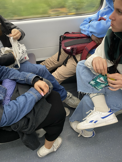 Asientos de la renfe con 3 chicas y 1 chico, el chico con sus piernas estiradas