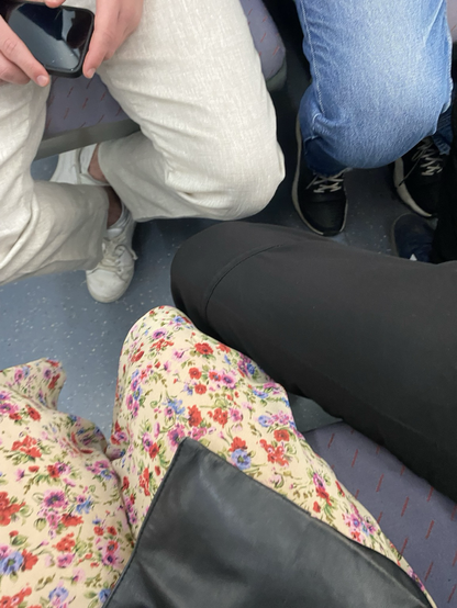 Chica sentada y a su lado hombre al lado ocupando au asiento con sus piernas abiertas