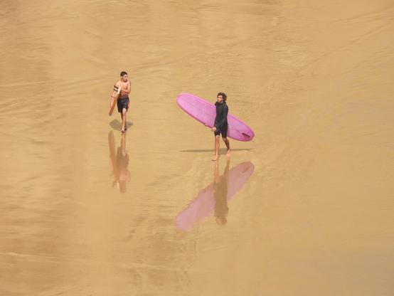 Photo de surfeurs avec leurs reflets sur la plage