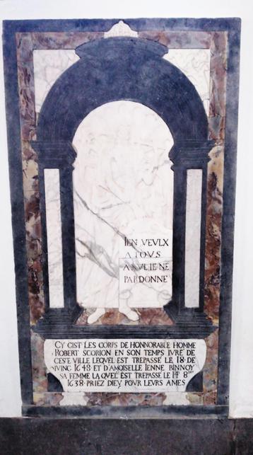 Pierre tombale en marbres multicolores apposée contre un mur. La Mort en très faible relief tient une devise. Le nom des défunts est inscrit en capitales en bas de la tombe.