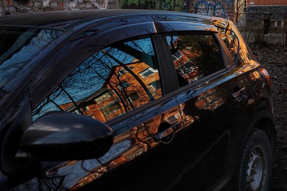 Close-up of a car window in which a red building is reflected. 