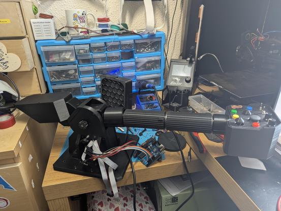a 3D printed helicopter collective with the control wires still needing to be tidied away, in the background chaos 