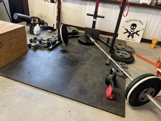 Wooden box, kettle bells, dumb bells and a bar in a landmine attachment on rubber flooring