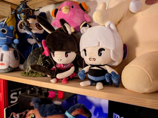 Plushies of Heavyblade Rabbit and Tassha from Rabbit & Steel sitting neatly on a shelf