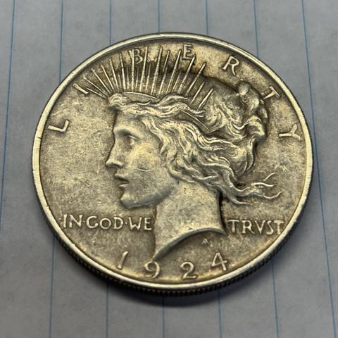 The obverse of a 1924 Peace silver dollar. Lady Liberty is looking to the left in profile with the word LIBERTY around the top of her head. The words IN GOD WE TRUST are across the coin, just below her chin. The year is at the bottom.