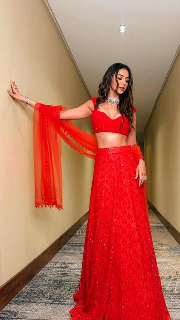 Rakul Preet Singh turns heads in a red lehenga by Sawan Gandhi, exuding grace and sophistication. The ensemble features a fitted georgette blouse with shimmering sequins and a subtle sweetheart neckline, paired with a flared lehenga showcasing diamond patterns. A delicate net dupatta with crystal work and pom-pom tassels adds ethereal charm. Styled by Tanisha Bhatia and Akshita Rai, with makeup by Salim Sayed and hair by Aliya Shaik, Rakul's look is completed with dazzling white stone jewelry from M K Jewels and Anmol.
