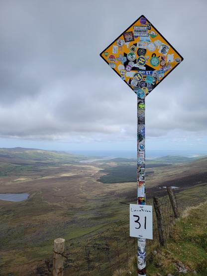 Sign covered with stickers on top of Connor Pass in Dingle 