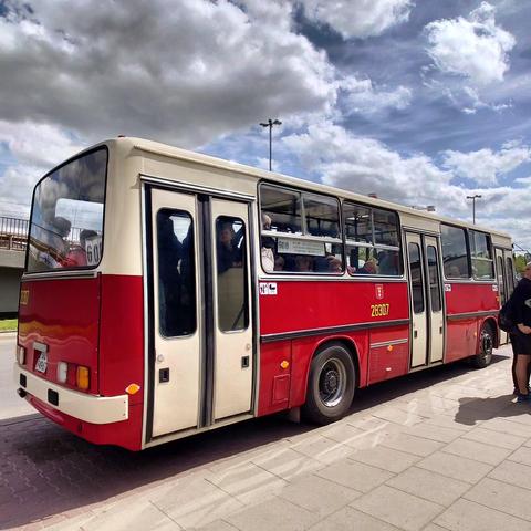 Ein Ikarus Bus von hinten rechts gesehen. Der Bus ist rot weiß. 