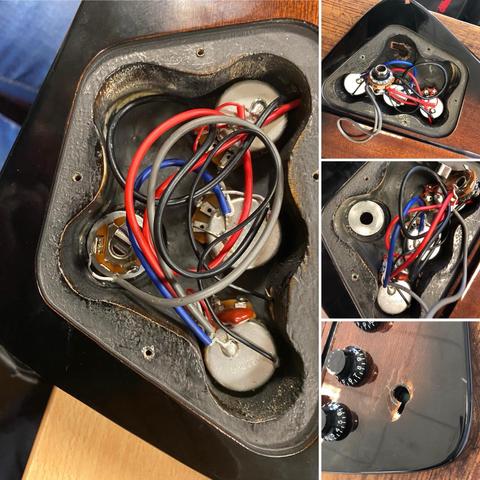 Image shows a close-up view of the internal wiring of an electric guitar. There are various colored wires (red, blue, and black) connected to metal components, including pots and a jack.