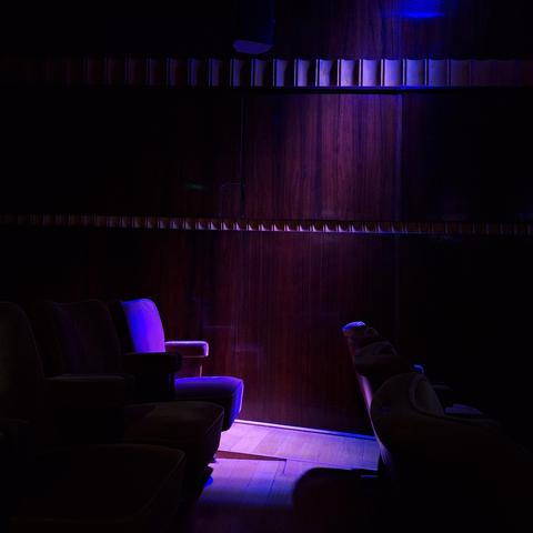 Un siège de cinéma de la salle "Studio 4" du Flagey, dans la pénombre et éclairé par une lumière violette qui lui donne un aspect velours très cinématographique.