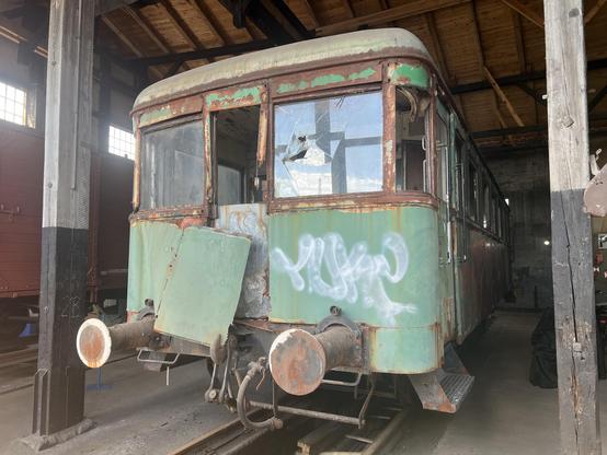 Grüner Beiwagen mit starken Rostspuren, insbesondere an sen Fensterrahmen.