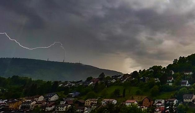 A screen grab from a wide angle movie looking down the Peterstal valley and across the Neckar valley to the large hill called the Königstuhl on the other side. The skies are very heavy grey due to a storm and a lightning strike is seen hitting the top of one of three large antenna towers on the hill.
