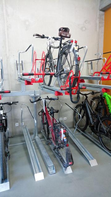 Ein rotes Patria-Reiserad steht unten in einer Fahrradschiene und ein Englisch-grünes Wanderer-Reiserad steht darüber in der Hubschiene der Fahrradgarage
