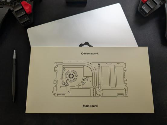 A framework mainboard upgrade box on top of a closed framework laptop with the included screwdriver