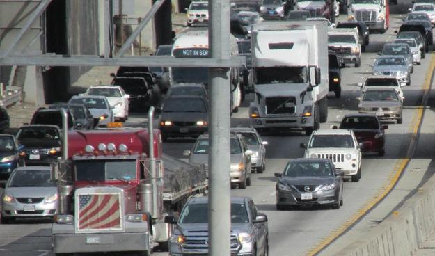 Diesel trucks travelling on heavily congested freeway.