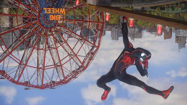 Foto de Miles Morales en una montaña rusa con un traje de Spiderman (¿2099?) de color negro y detalles rojos y blancos. Lleva una capucha y tanto manos como pies son rojos. La araña del pecho es gigante, se alarga hasta la cintura. Sus grandes ojos desprenden luz.
Spiderman está en pose foto: apoyado boca abajo sobre una mano mientras flexiona una pierna y la otra la estira. La otra mano hace un gesto tocándose la frente con dos dedos.
Al fondo podemos ver una noria y la ciudad de Nueva York. En la noria pone Big Wheel y, aunque se ve bastante grande, no se alcanza a ver a gente en el interior.
La foto está girada 180º.