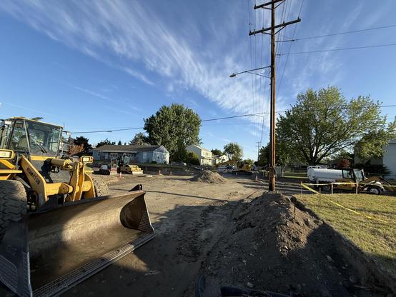 An intersection of two streets torn down to dirt filled with construction vehicles
