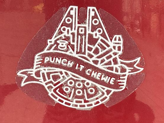 a due-cut decal of the millenium falcon with a sash wrapping it reading: ‘punch it chewie’