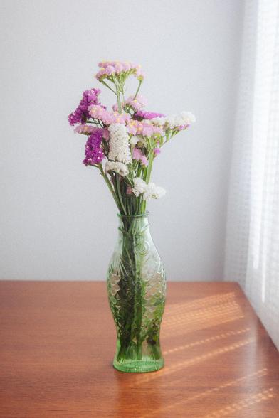 2 - How I usually edit my pictures. Photograph of a fish-shaped pot filled with colorful flowers on a wooden table, with sunlight filtering through the curtains. The scene is well lit and has a dreamlike effect.