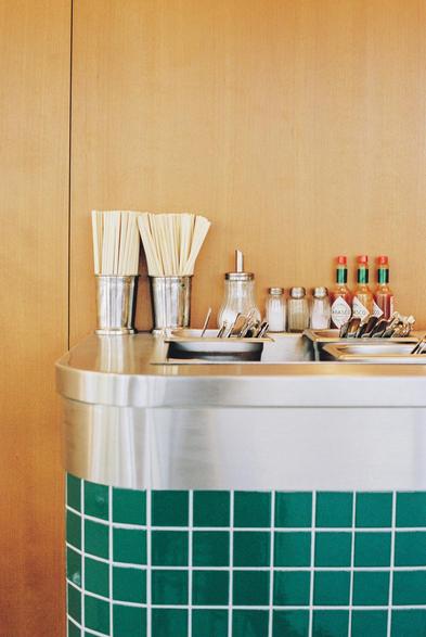 2 - Film, shot on Portra 400. Photograph of the corner of a counter in a restaurant with chopsticks, a sugar bowl, several salt shakers, and bottles of hot sauce.