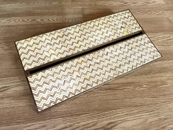 A two tiered guitar pedal board with zigzag patterned plywood and walnut edging