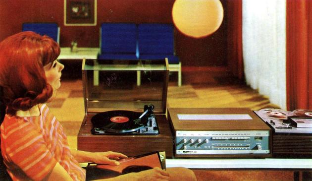 Woman listening to music from a vintage record player and stereo system in a 1970s-style living room.