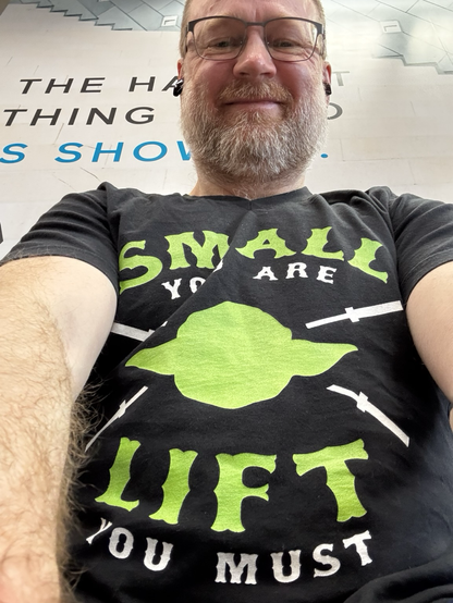 Wearing T-shirt with yoda head crossed with empty barbells with the words “small you are; lift you must”.
