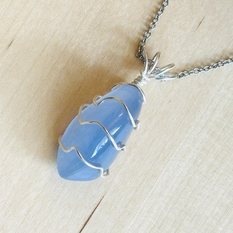 An oblong sky blue stone with the silver wire creating a rippled effect along the stone. The pendant is on a silver chain. 