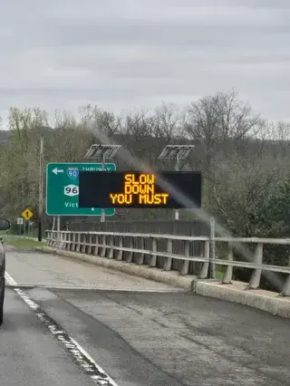 highway sign: slow down you must