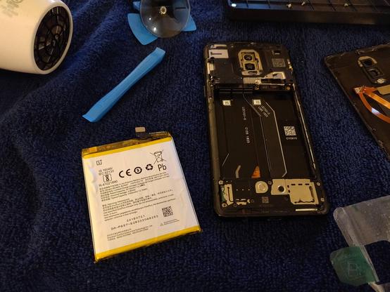 The old battery has been removed from the phone by pulling on a tab that was attached to the battery.  The tab peeled off of the battery and is visible to the right of the phone.  Unfortunately, the tab ripped apart while attaching it to the new battery, but the adhesive in the phone was also weakened so I don't think it's still needed.