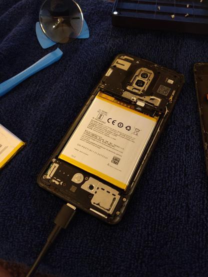 The new battery is installed in the phone, with the back cover still removed.