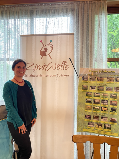 Frau vor Aufsteller „Zimtwollr“ und Plakat mit deutschen Schafsrassen