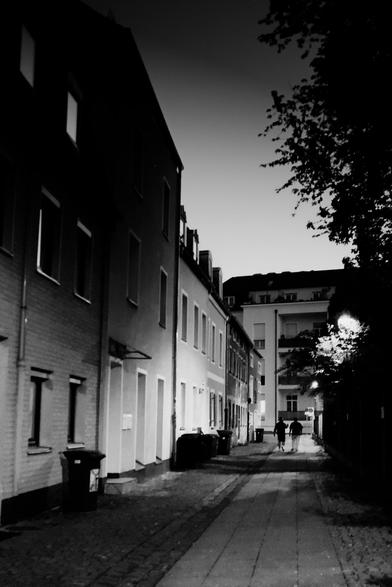 Black and white photo of a street with two people walking away