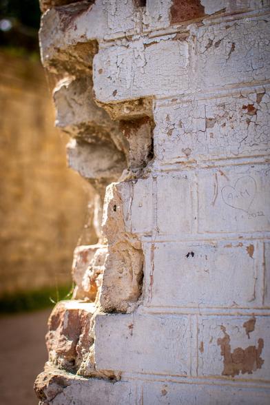 A closeup of a corner of a brick wall that was damaged and then painted over. Steam Machine House, Park Babelsberg, Potsdam, 1 May 2025. Nikon D5600, Nikkor DX 35 mm ƒ1.8G, ISO 100, -0.3 ev, ƒ3.2, 1/800s