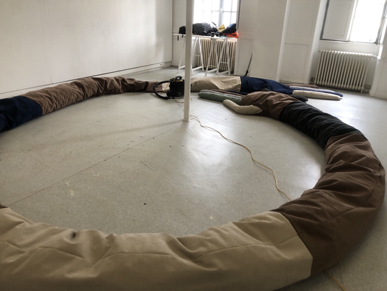 Le traversin déployé au sol, formant un cercle. Les deux mains se rejoignent.