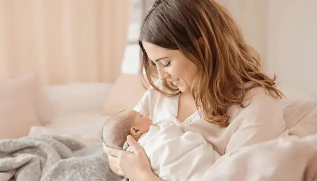 Mother gently cradling newborn in a softly lit, cozy room with pastel colors, symbolizing strength and nurturing care during postpartum recovery.